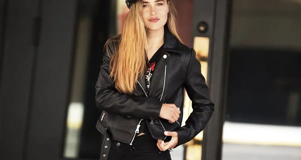 Dziewczyna w czarnej ramonesce i czapce, emanująca pewnością siebie w stylu glam rock.