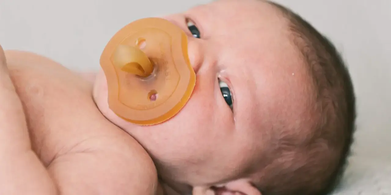 Neugeborenes Baby mit Schnuller. Die Frage "ab wann Schnuller geben" beschäftigt viele Eltern.