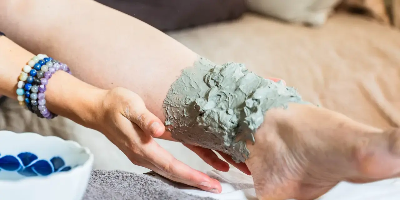 Application d'argile verte sur une jambe, profitant de ses bienfaits détoxifiants et apaisants pour la peau.