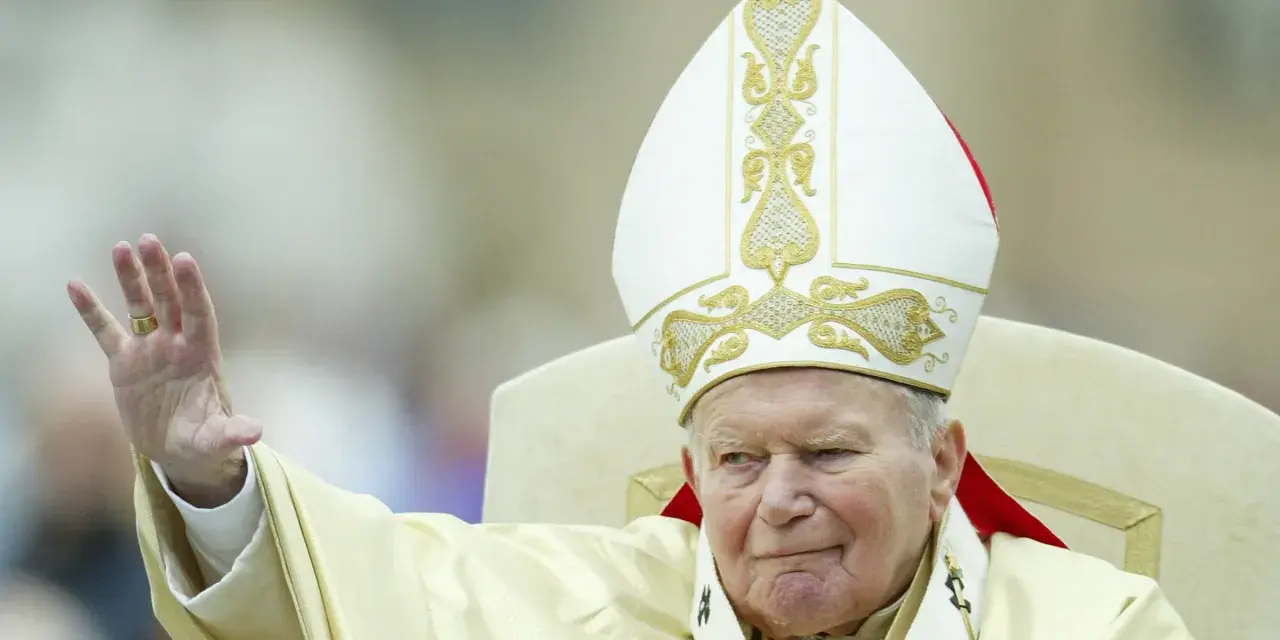 Papież Jan Paweł II w białej mitrze z haftem, pozdrawia wiernych. Jego dłoń z pierścieniem jest uniesiona. Codzienna modlitwa do św. Jana Pawła II.