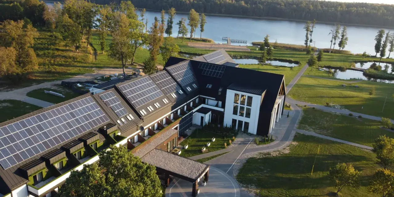 Nowoczesny hotel z panelami słonecznymi nad jeziorem, idealny na Mazury all inclusive.