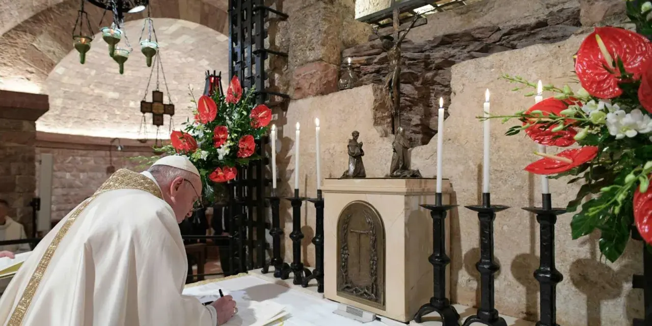 Papst Franziskus schreibt in einem Buch, während Kerzen und rote Anthurien brennen. Dies erinnert an die Bedeutung einer Enzyklika, eines wichtigen päpstlichen Schreibens.