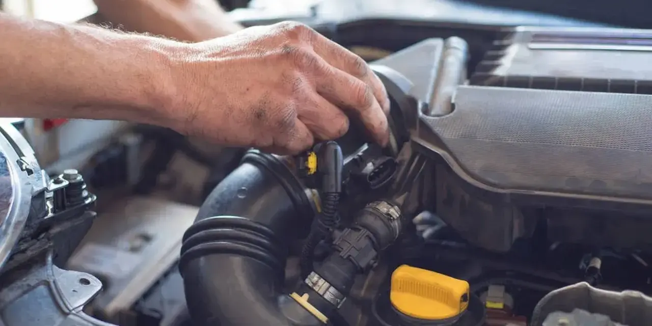 Mechanik pracuje przy silniku, regulując układ dolotowy.