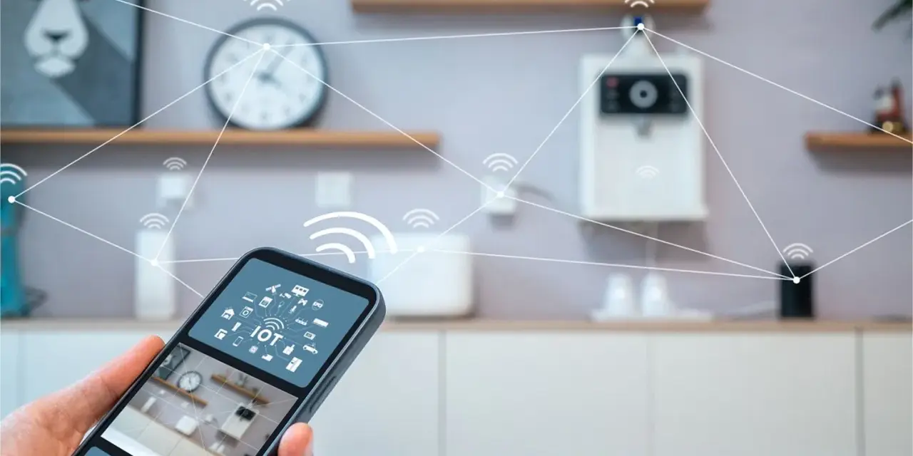 En hand håller en smartphone med en smart life app. I bakgrunden syns ett kök med uppkopplade enheter.