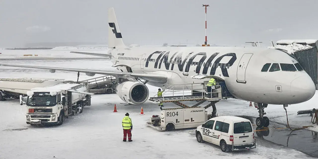 Samolot Finnair na lotnisku w śnieżny dzień. Pracownicy obsługi naziemnej przygotowują samolot do lotu. Czy do Finlandii można lecieć na dowód?