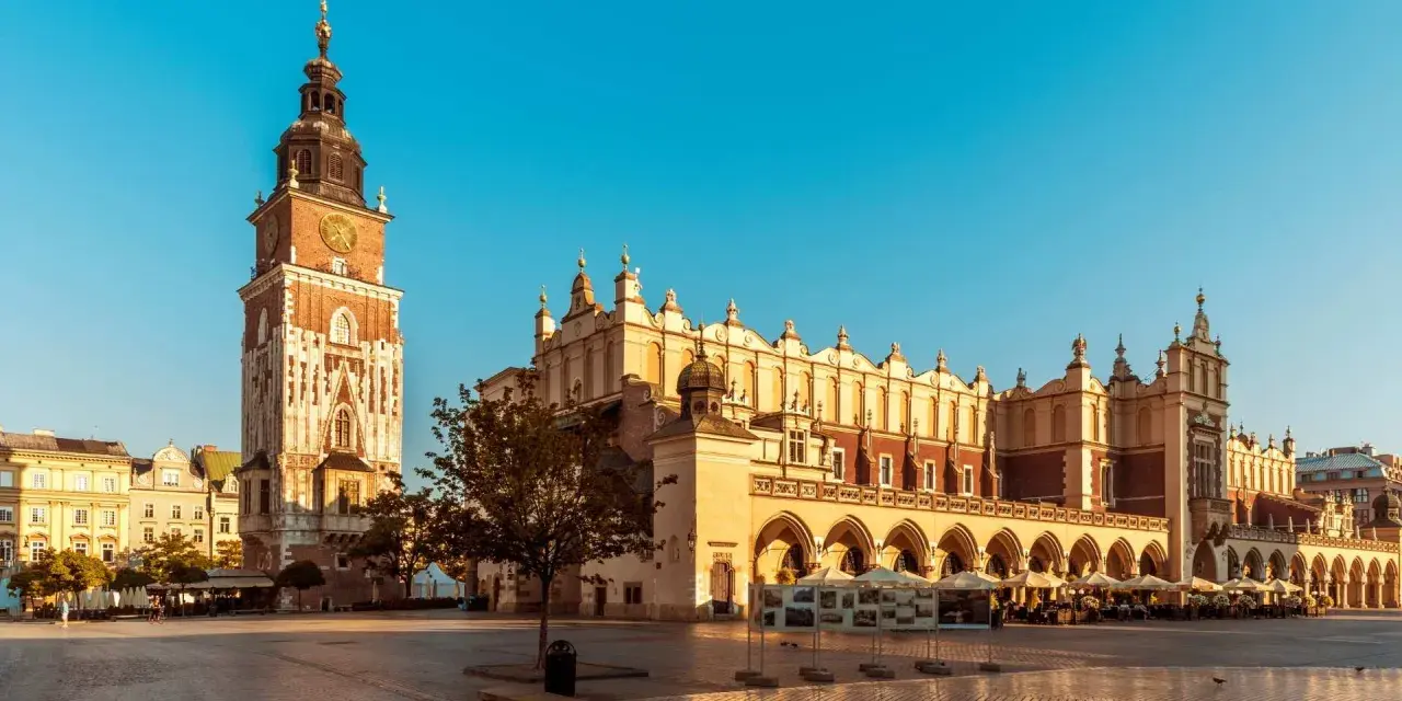 Rynek Główny w Krakowie z Sukiennicami i Wieżą Ratuszową w słoneczny dzień.