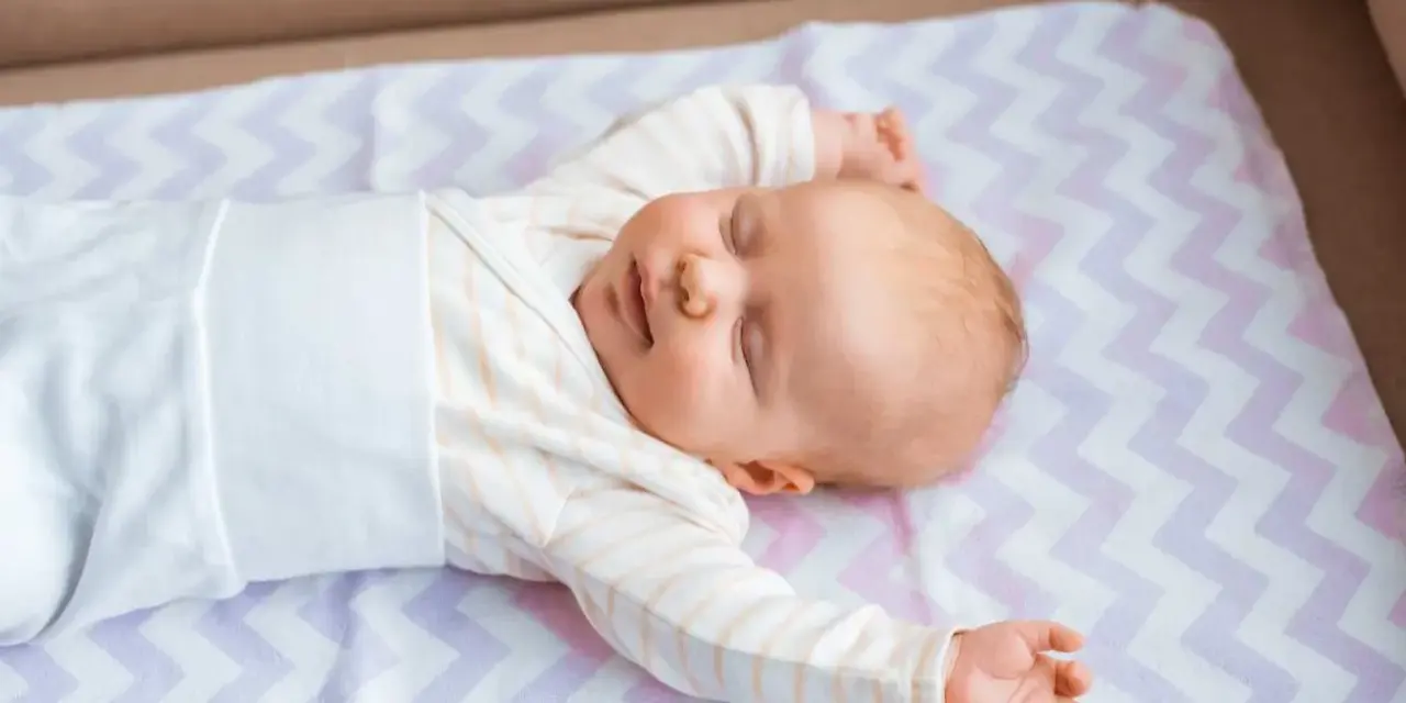 Śpiące niemowlę na kolorowej macie. Średnio główka niemowlaka rośnie ok. 1-2 cm miesięcznie.