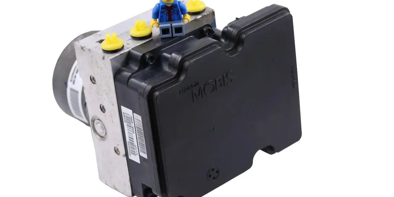 Moduł ABS Hyundai Mobis. Może być powiązany z błędem DTC C1201 Toyota. Figurka Lego na górze.