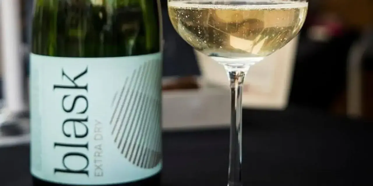 Butelka i kieliszek z musującym winem. To dobre wino słodkie, idealne na letnie wieczory.