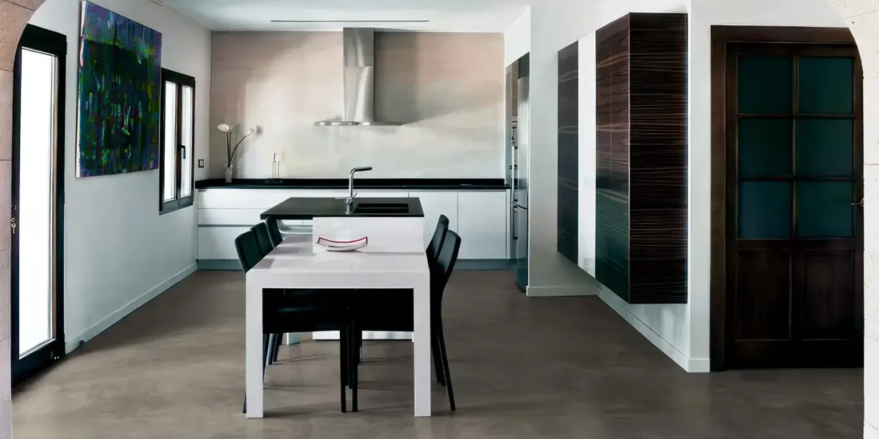Modern kitchen with a dining area. The **pavimento in cemento per interni costi** is visible, offering a sleek and contemporary look.