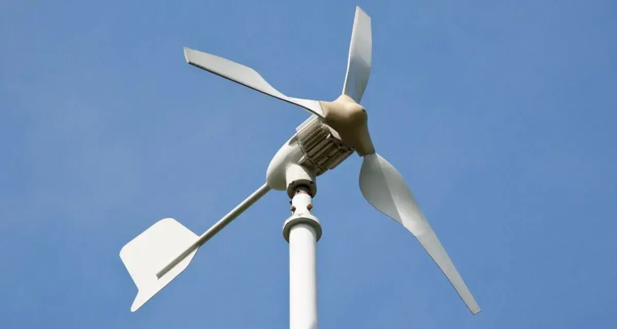 Mała turbina wiatrowa z białymi łopatami i ogonem, idealna jako jaka turbina wiatrowa do domu, na tle błękitnego nieba.