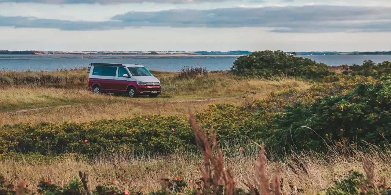 Husbil parkerad vid en kustväg i Danmark, redo för ett äventyr. En perfekt roadtrip danmark-upplevelse.
