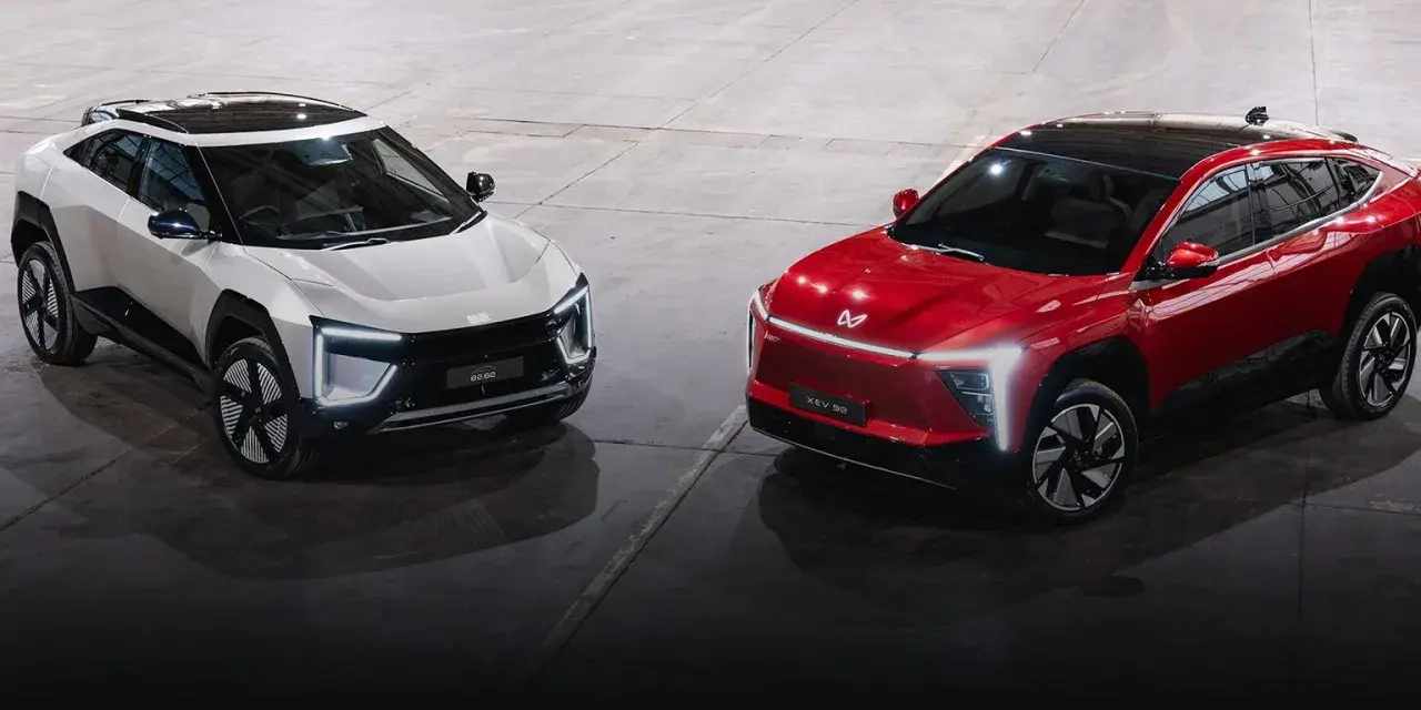Dwa futurystyczne SUV-y, biały i czerwony, marki Mahindra, prezentują nowoczesny design z ostrymi liniami i LED-owym oświetleniem.