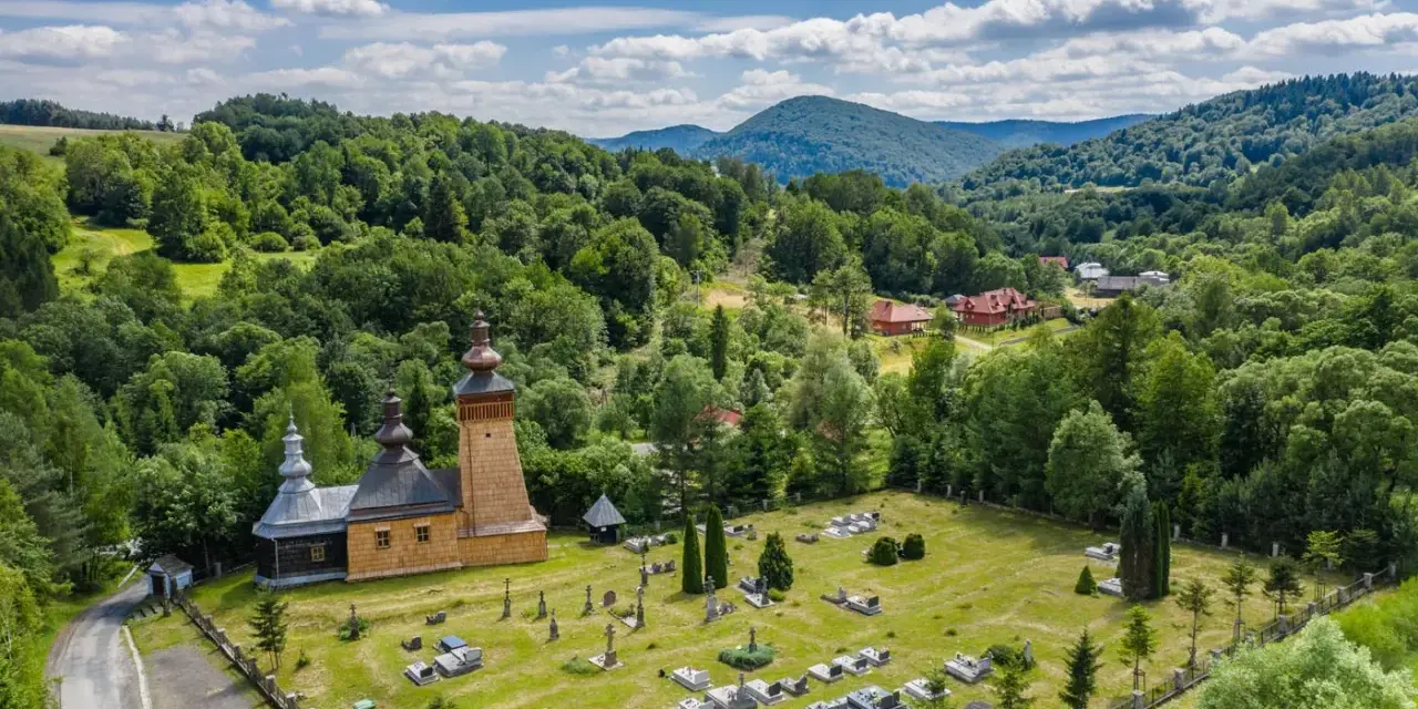 Drewniana cerkiew z cmentarzem w malowniczym krajobrazie Beskidu Niskiego.