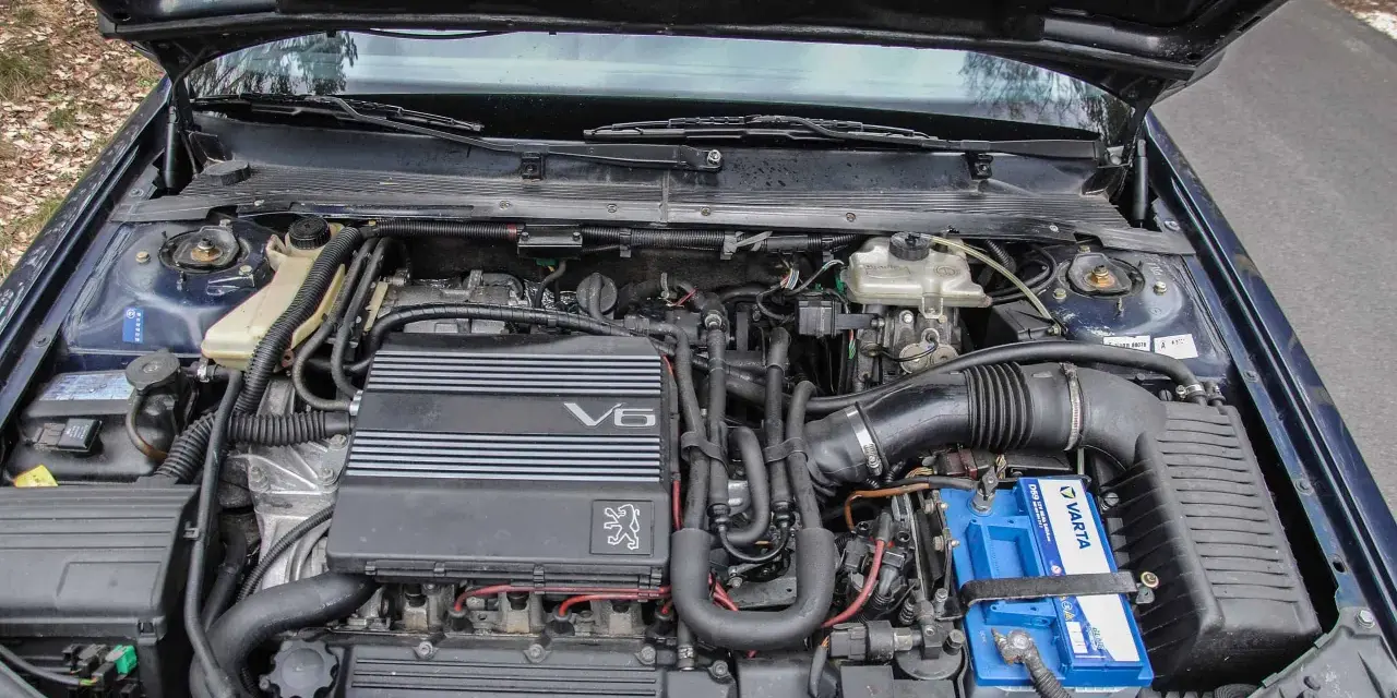 Silnik V6 wolnossący Peugeot, z widocznym akumulatorem Varta i elementami układu dolotowego.