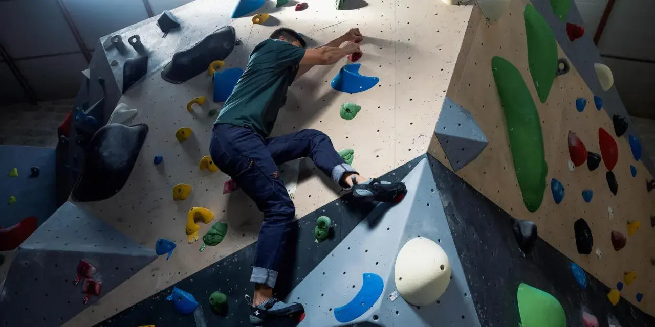 Mann klettert an einer bunten Kletterwand, die aussieht, als ob sie jemand selber bauen könnte.