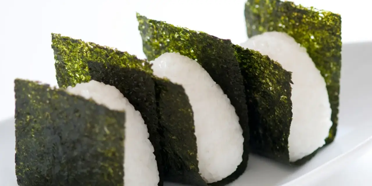 Trzy ryżowe onigiri owinięte w arkusze nori. Prosty sposób, jak przygotować nori do sushi, by nadać mu chrupkość i smak.