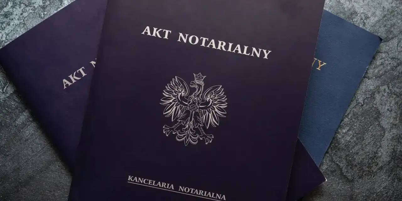 Stos dokumentów, na wierzchu ciemnogranatowy akt notarialny z godłem Polski.