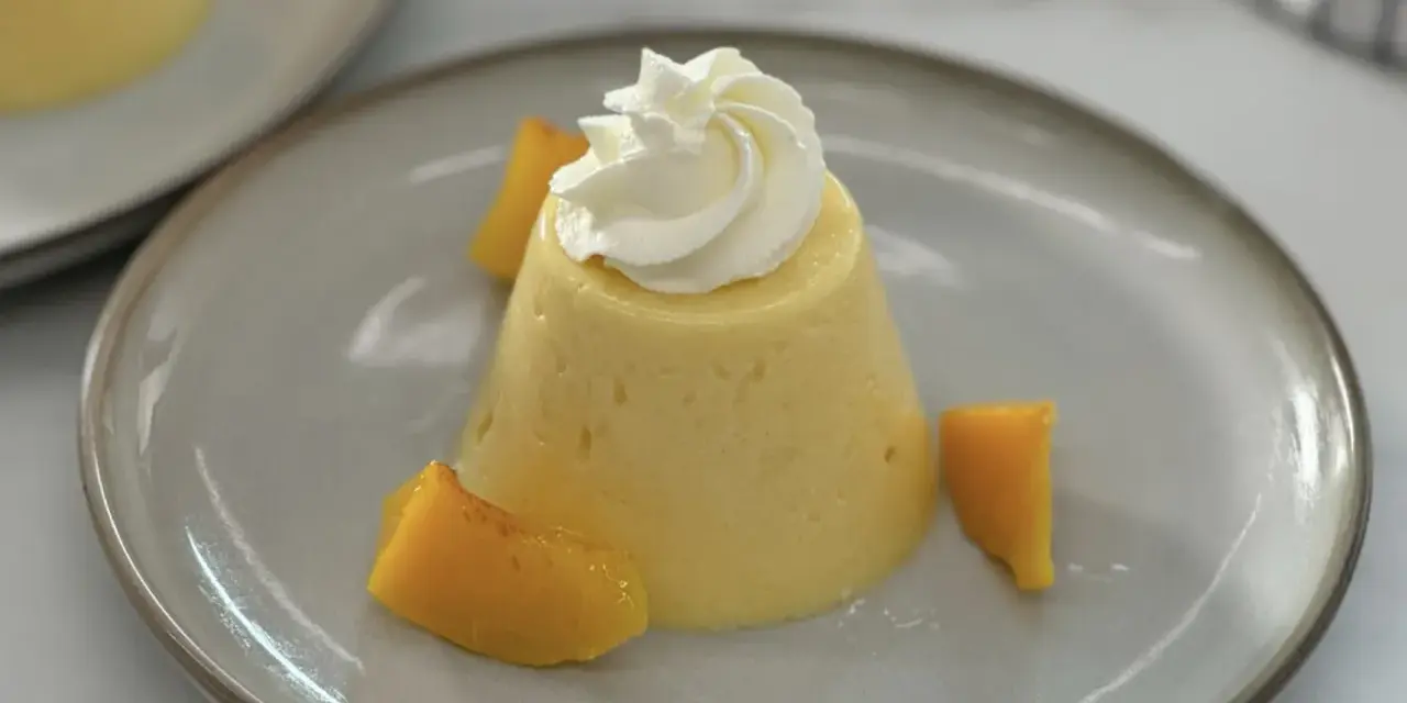 Postre de melocotón en almíbar con crema batida y trozos de melocotón.