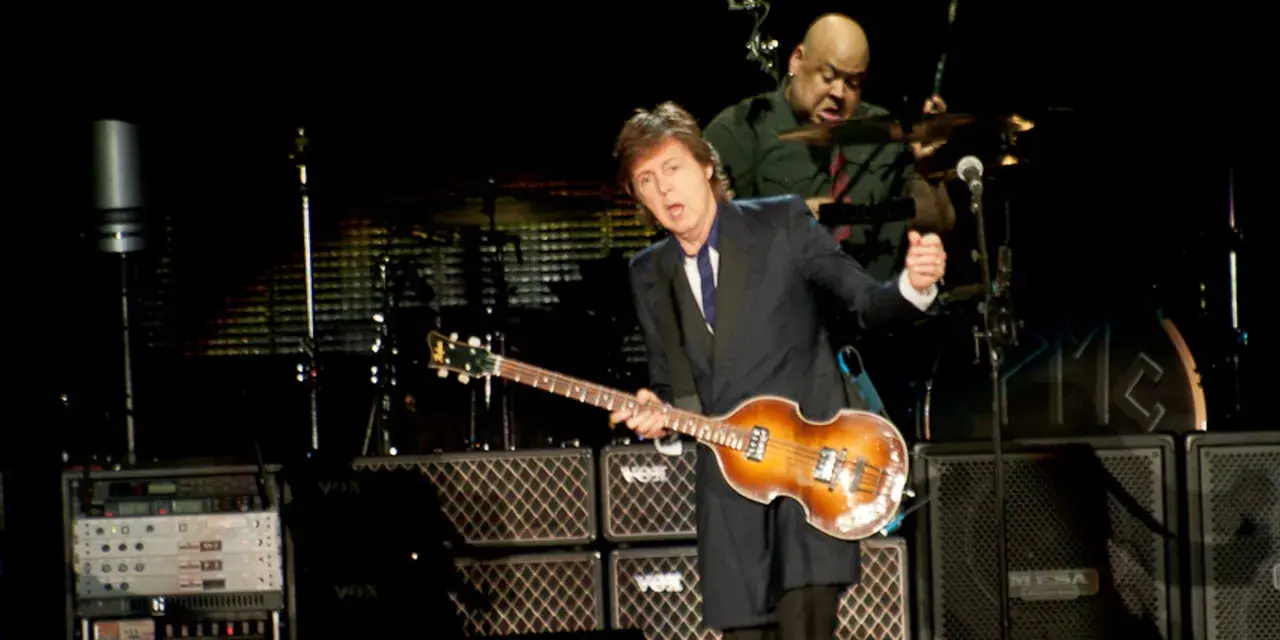 Paul McCartney na jednym ze swoich koncertów, grając na gitarze basowej. W tle perkusista.