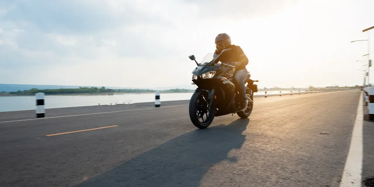 Motocyklista przemierza malownicze trasy motocyklowe pomorskie w blasku zachodzącego słońca.