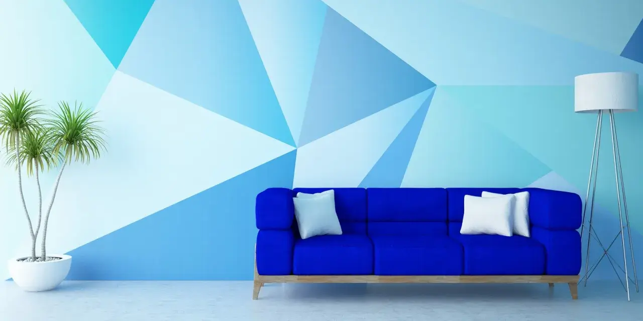 Nowoczesny salon z niebieską kanapą i geometrycznymi wzorami na ścianie malowanymi farbą.