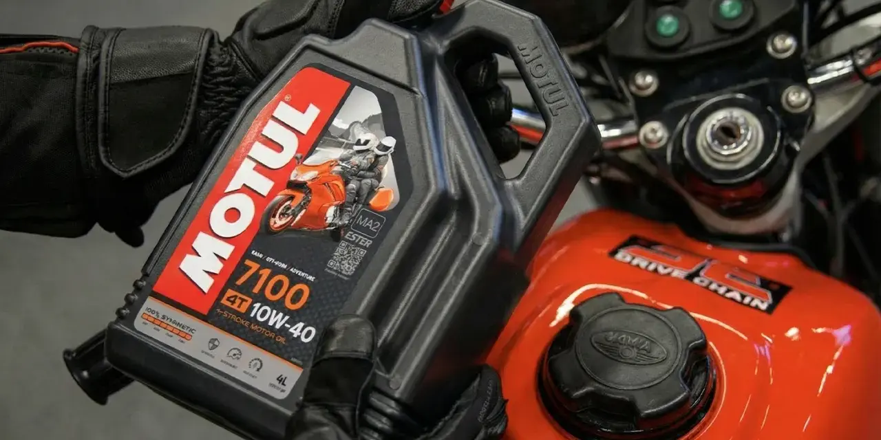 Ręce w rękawiczkach trzymają olej Motul 7100 10W-40. Pytanie: co ile wymieniać olej w motocyklu?