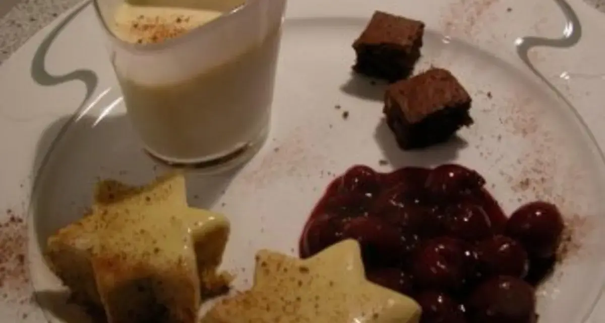 Sterne aus Zimtstern-Eis, garniert mit Kirschen und Brownies, serviert auf einem Teller.