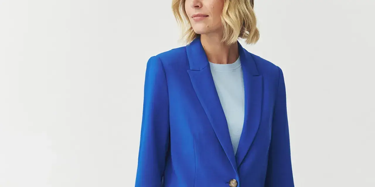 Kobieta w eleganckim, niebieskim żakiecie. Kolor kobaltowy a chabrowy idealnie podkreśla jej urodę.