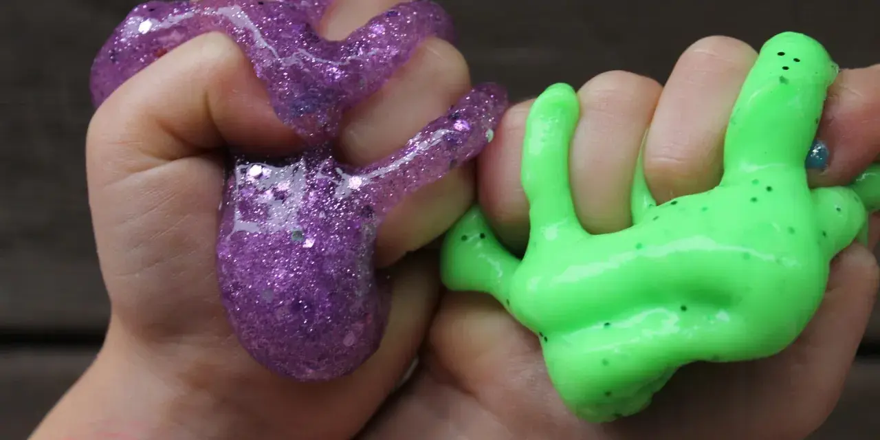 Hände formen lila Glitzer-Slime und grünen Schleim. So macht man Slime: Spaß für Kinder!