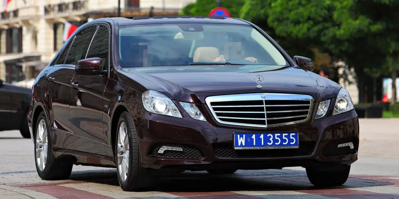 Ciemnobrązowy Mercedes z tablicami dyplomatycznymi W 113555, jadący po pasach.