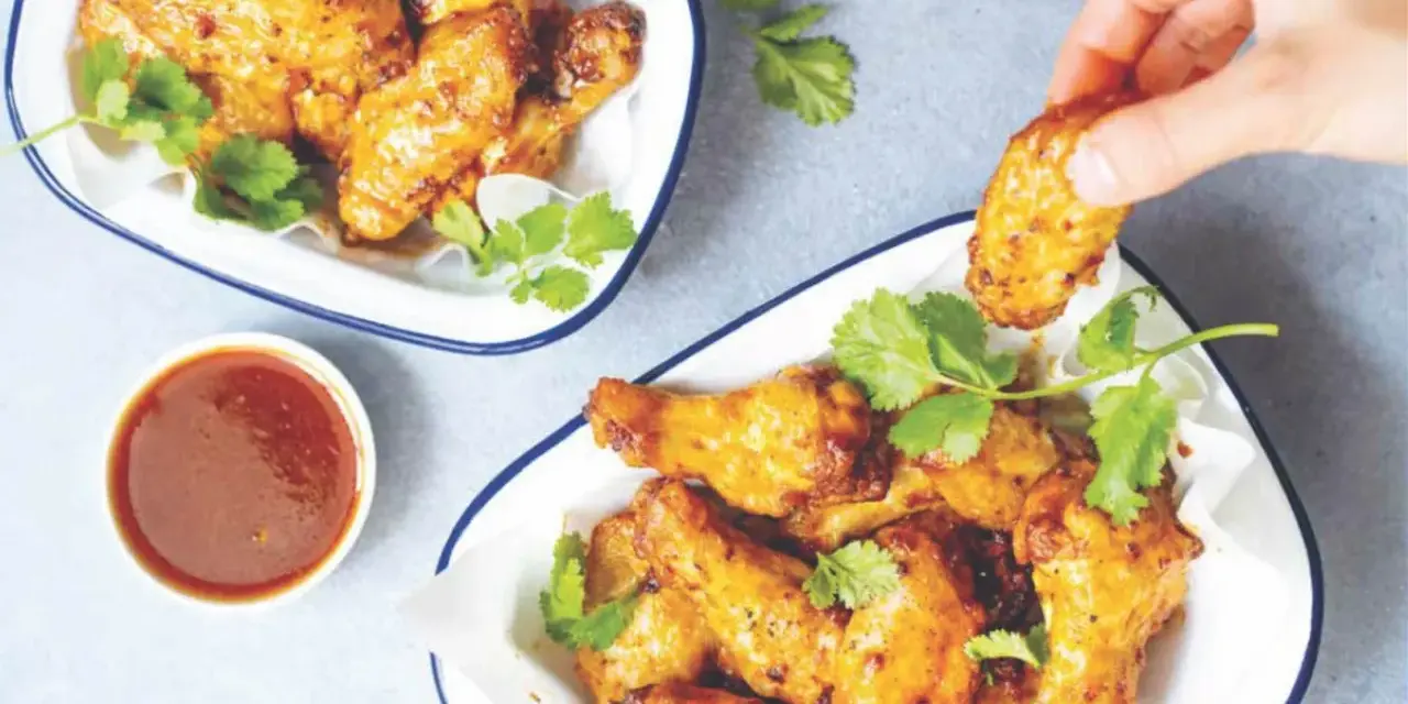 Chrupiące skrzydełka z airfryer, podane z sosem i świeżą kolendrą. Idealna przekąska na imprezę.