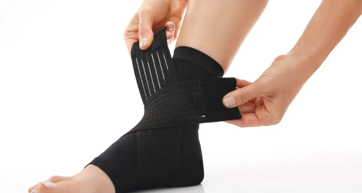 Hands adjust a black compression ankle brace, demonstrating how compression therapy works for support and recovery.