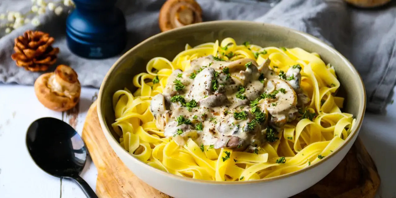 Un plat de pâtes tagliatelles garni d'une onctueuse sauce pour pâtes farcies aux champignons, parsemé de persil frais.
