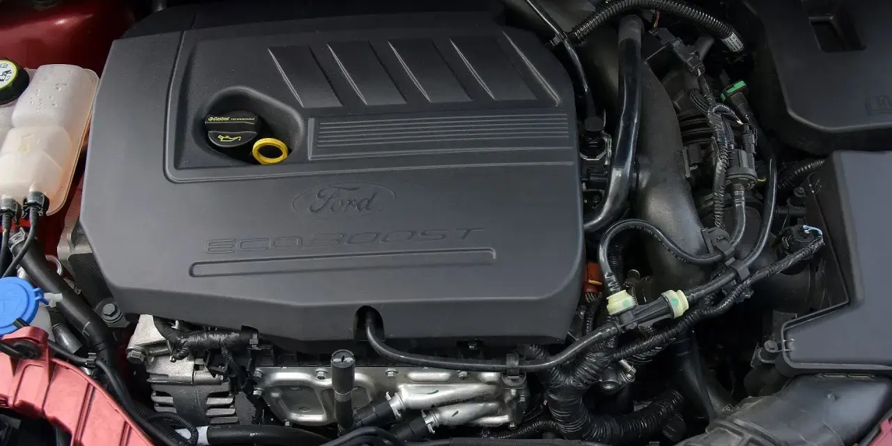 Silniki Ford Focus MK3 EcoBoost. Widok komory silnika z widocznym czarnym plastikowym elementem z napisem "Ford EcoBoost".