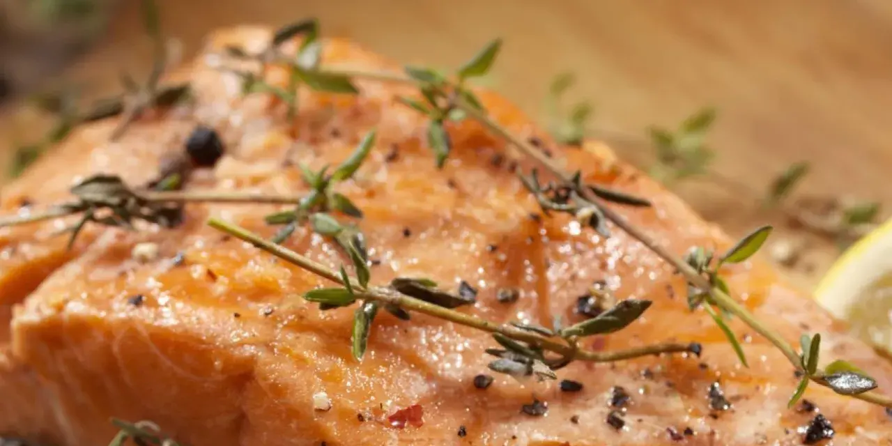 Delicioso salmón al horno, jugoso y dorado, con hierbas frescas y pimienta.