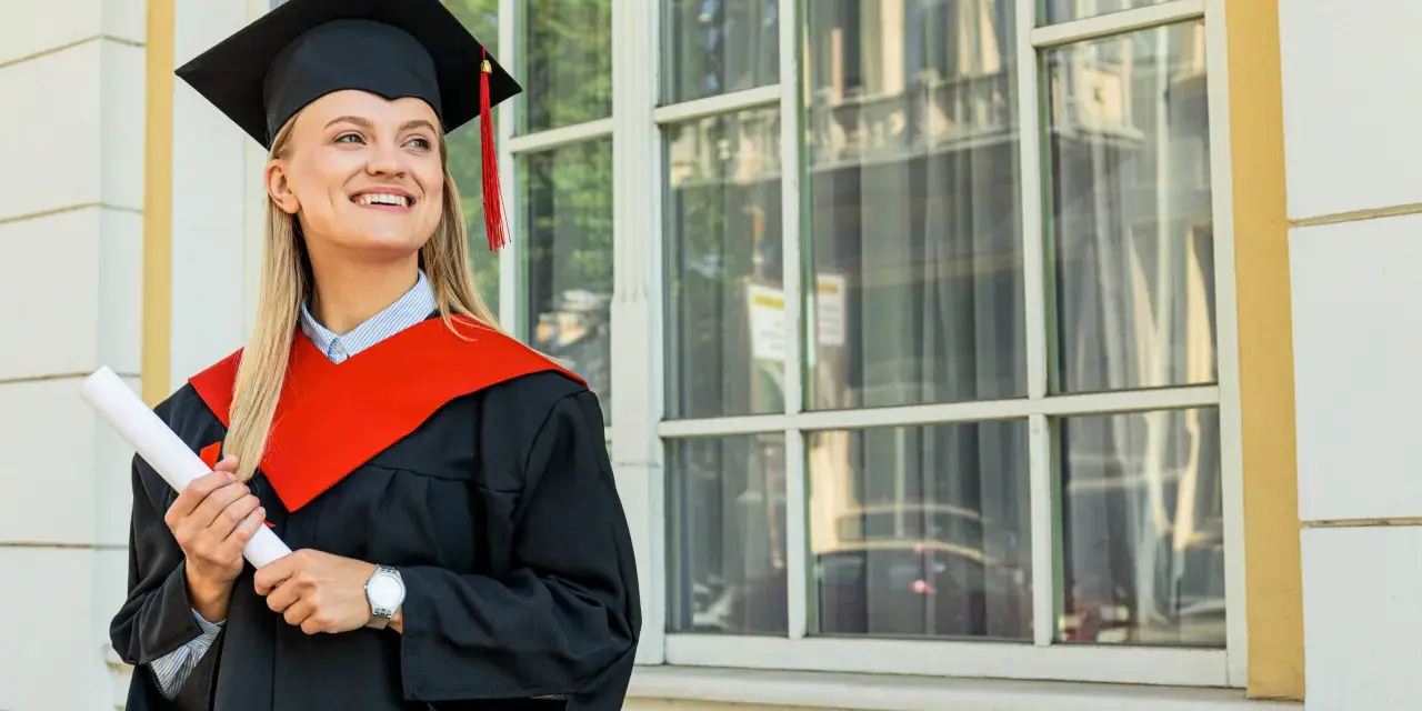 Uśmiechnięta absolwentka z dyplomem, w todze i birecie, zastanawia się, co to studia MBA i jakie możliwości otwierają.