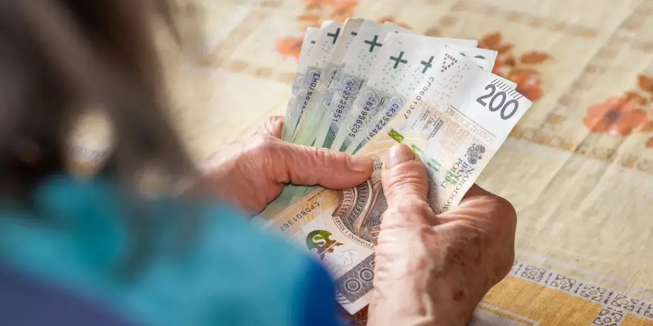Dłonie starszej osoby liczą banknoty 200 zł. To może być pomoc w utrzymaniu, gdy przychodzi emerytura wdowia.