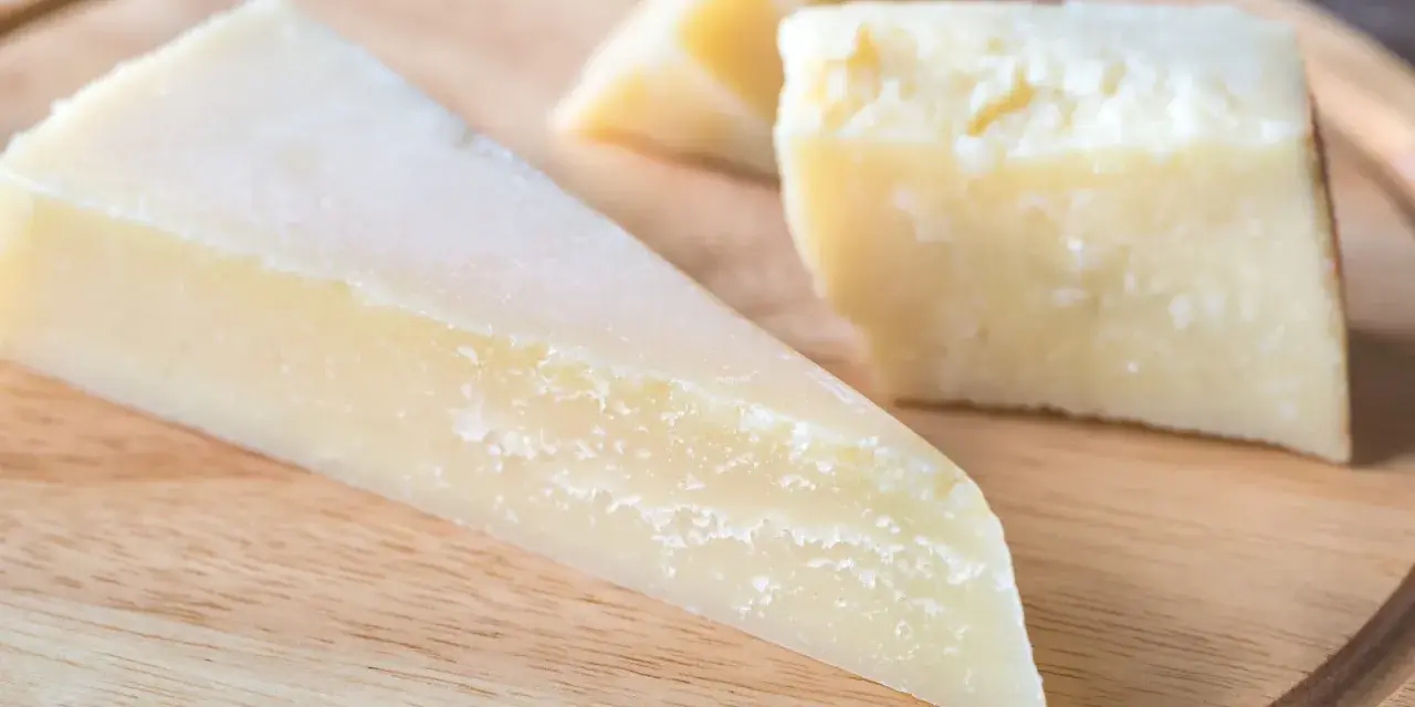 Kawałki twardego, żółtego sera na desce. Szukasz pomysłów, czym zastąpić parmezan?