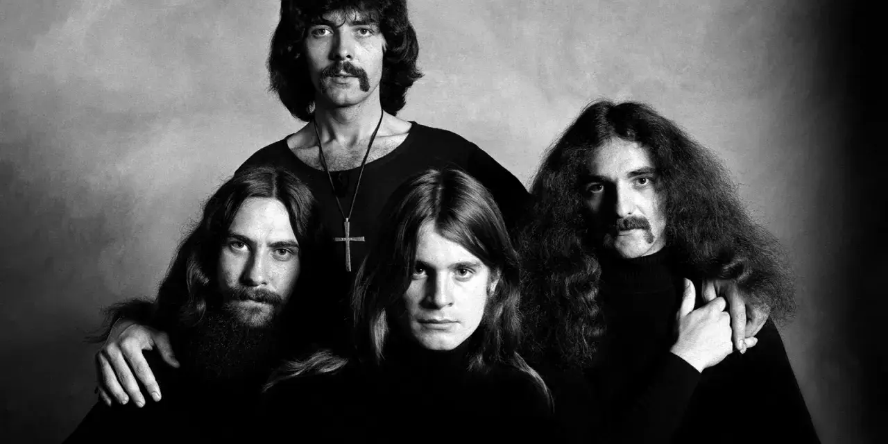 Czarno-białe zdjęcie zespołu Black Sabbath. Czterech mężczyzn z charakterystycznymi fryzurami i wąsami pozuje do portretu.