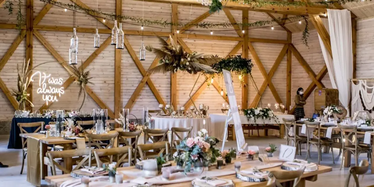 Drewniana stodoła udekorowana na **slow wedding**. Neonowy napis "I was always you", wiszące butelki, kwiaty i girlandy tworzą magiczną atmosferę.