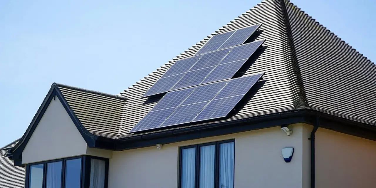 Panele fotowoltaiczne na dachu domu, działające jako agregator energii, łapią promienie słoneczne.