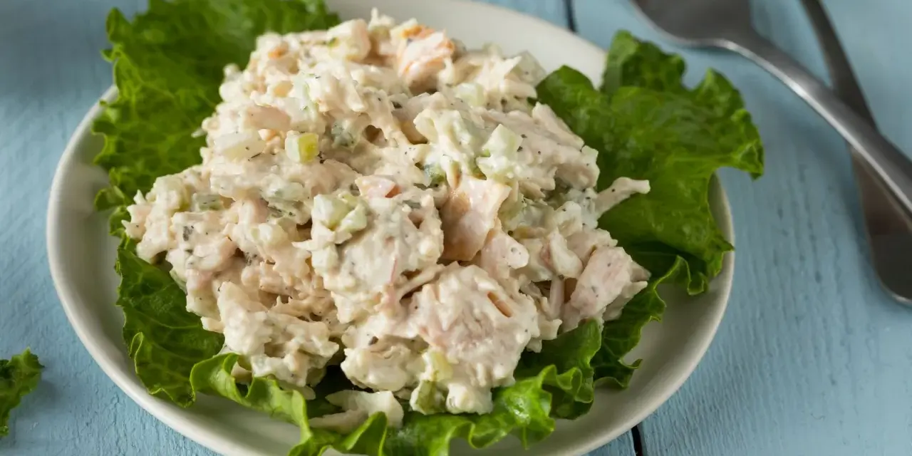 Un piatto di insalata di pollo della nonna, cremosa e ricca, servita su foglie di lattuga croccante.