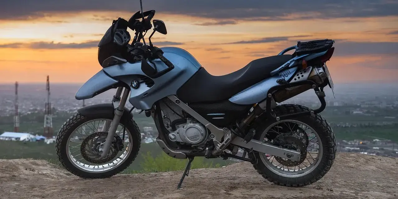 Niebieski motocykl BMW na wzgórzu, gotowy do podróży po Litwie, gdzie obowiązują ograniczenia prędkości.