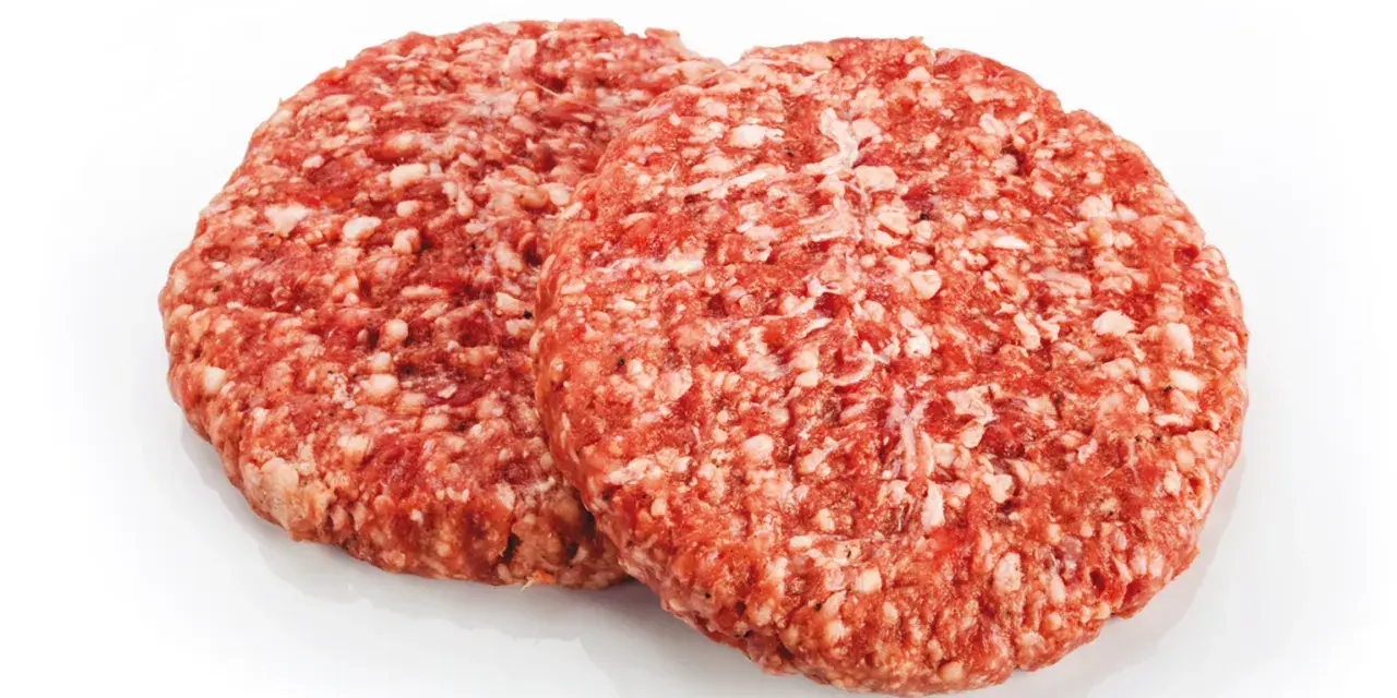 Dwa surowe kotlety mielone na burgery na białym tle.