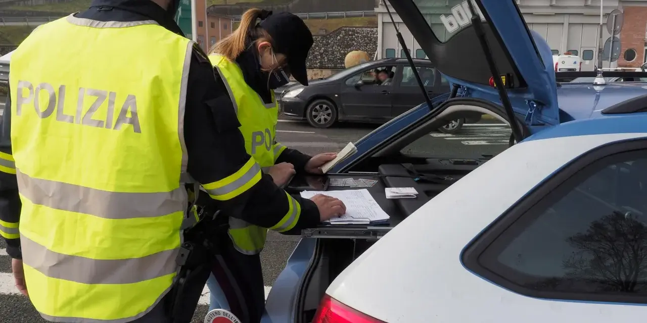 Agenti della Polizia Stradale controllano documenti, forse per un caso di targa clonata, durante un posto di blocco.