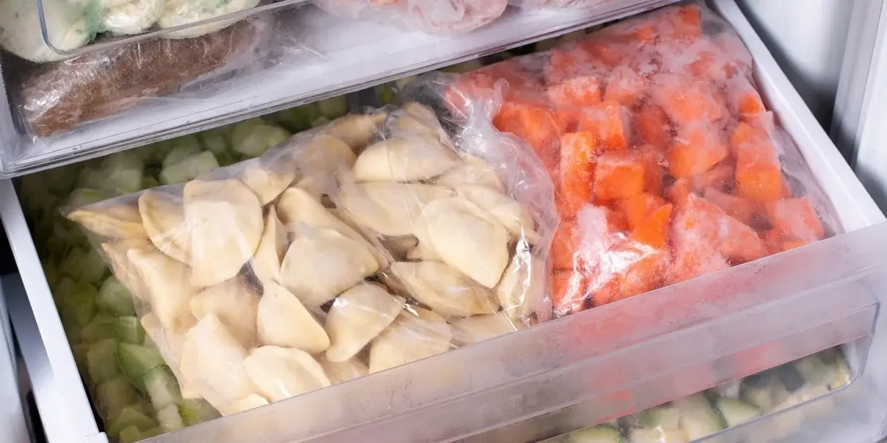 Zamrożone pierogi i warzywa w woreczkach w zamrażarce.