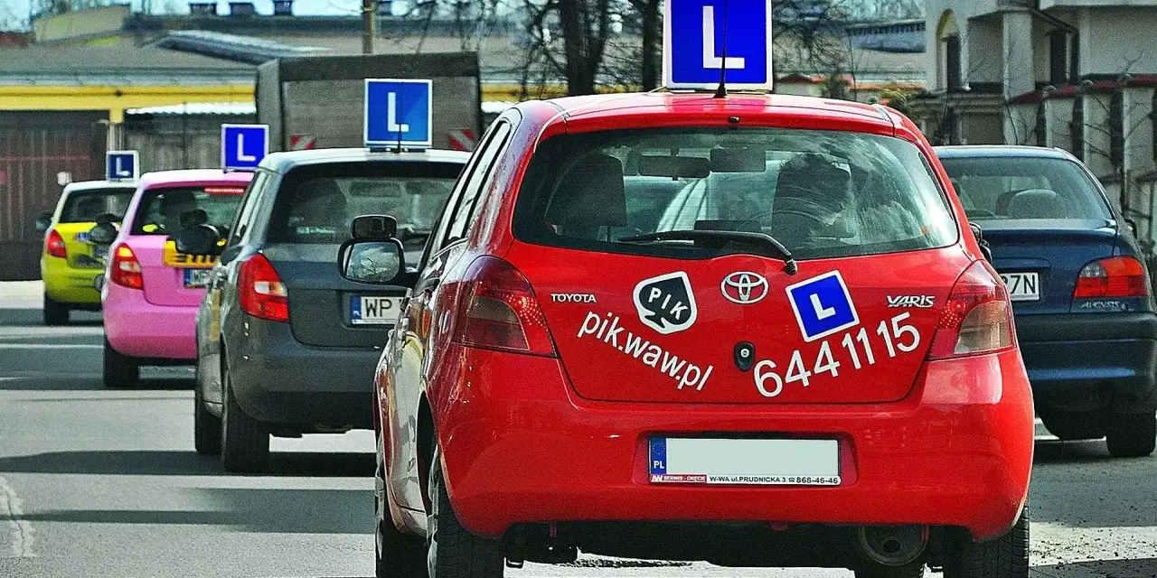 Czerwony samochód nauki jazdy z literą "L" na dachu. Zastanawiasz się, ile zarabia instruktor jazdy?