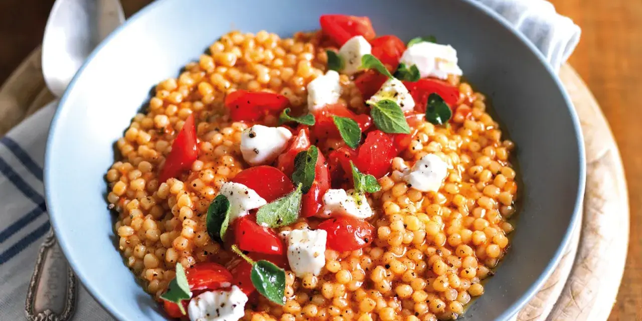 Fregola sarda ricetta originale: pasta tostata con pomodorini freschi, mozzarella e basilico, un piatto estivo profumato.