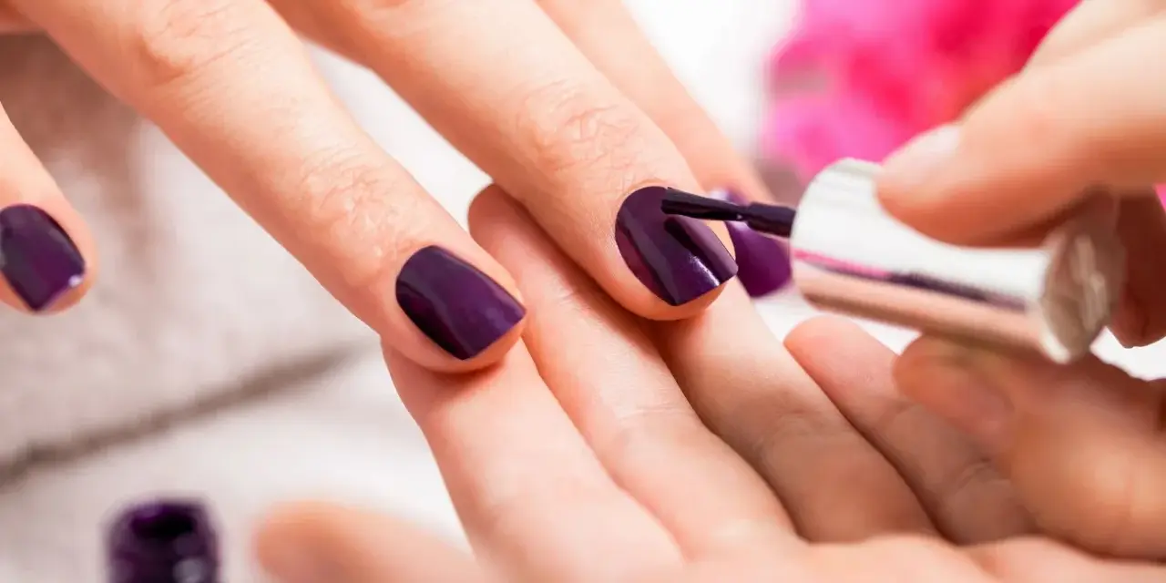 Applicazione smalto viola su unghie. Scopri come usare la fibra di vetro per unghie per un look impeccabile.